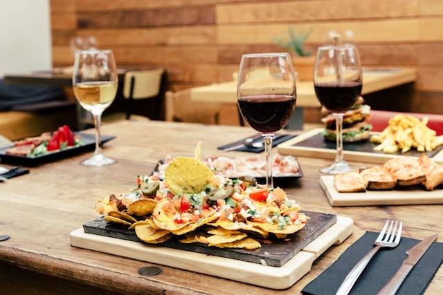table set with nachos and two glasses of wine